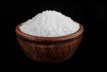 Clay cup with salt on a black background. table salt.
