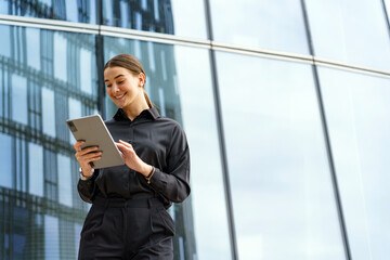 Business professional engaging with a tablet outdoors near a modern glass building