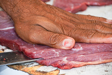 m&atilde;o cortando carne