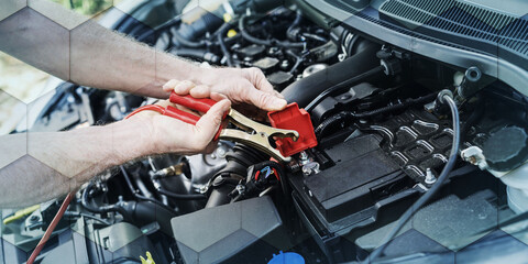 Hands of car mechanic using car battery jumper cable, geometric pattern