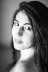 Naklejka premium black and white studio portrait of young Latina looking at the camera from over the shoulder 