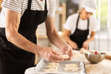 Baker's hands fold pieces of dough on baking sheet