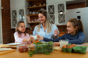 Happy family enjoying a nutritious breakfast together in a modern kitchen, with a mother pouring a glass of milk for her daughter while preparing a delicious meal