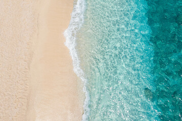 A bird's eye view of rolling waves on the beach, clear blue  sea
