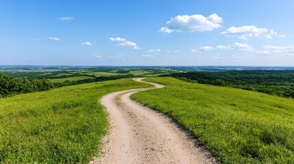 Fototapeta premium Winding dirt road on grassy hilltop, scenic countryside view, summer day, travel
