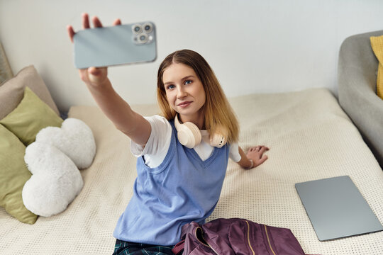 A teenage girl takes a selfie on her bed, highlighting youth culture in her stylish room.