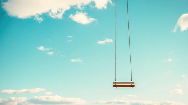 Empty swing suspended in bright blue sky evokes feelings of nost