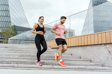 Fototapeta premium Couple enjoys a morning run down the stairs in an urban park with modern architecture