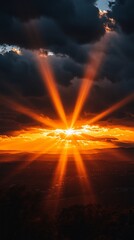 Dramatic sunset rays pierce dark clouds over landscape