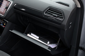 Open glove compartment with a folder of service documents in a car. History service book. Open glove compartment with a folder of documents in car. Owners manual handbook. Air vent.