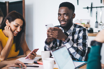 Multiracial coworkers using gadgets during break at work