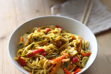 Bowl of stir fry vegetables and noodles, served on the table. Selective focus.