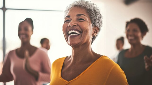 Elderly woman smiling joyfully in a group fitness class with natural light streaming through the windows, highlighting active aging and positivity.