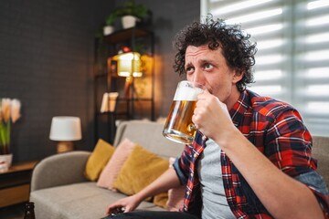 Man drinking beer while watching tv at home