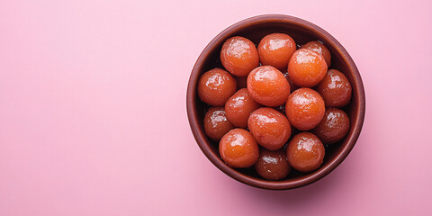 A bowl of gulab jamun placed on a pink background, offering a bright and minimalist composition of this popular Indian dessert.