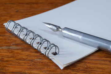 A fountain pen with a pen and a notebook on a wooden table