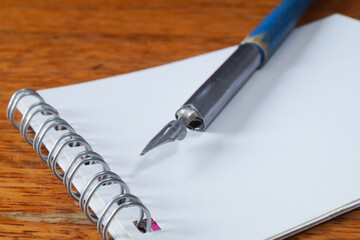 A fountain pen with a pen and a notebook on a wooden table