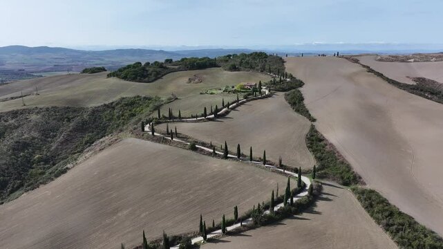 A drone captures the winding zig zag road at La Foce, Tuscany. The lush greenery, cypress-lined paths, and rolling hills create an unforgettable view of Italy&rsquo;s natural beauty.