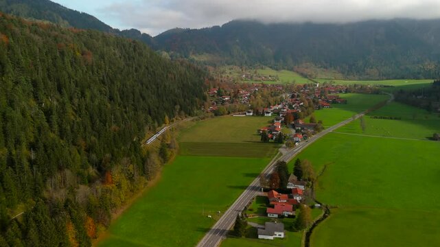 Autumn aerial view of a regional train arriving at Bayrischzell station, Germany. The scene is filled with golden trees and breathtaking Bavarian landscapes on a crisp fall day