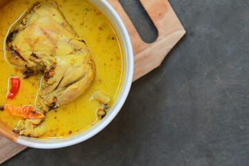 Famous Indonesian chicken curry, served in a bowl. Isolated on gray table. With copy space.
