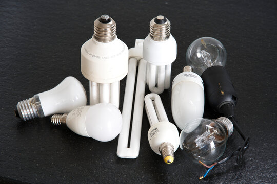 Old and technologically obsolete models of energy-saving light bulbs on black background.