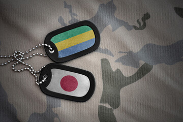 vintage army blank, dog tag with flag of gabon and japan on the khaki texture background. military...