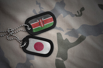 vintage army blank, dog tag with flag of kenya and japan on the khaki texture background. military...