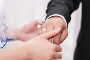 The bride places a gold wedding ring on the groom's finger. Traditional ceremony of exchanging wedding rings.