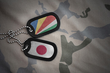 vintage army blank, dog tag with flag of seychelles and japan on the khaki texture background....