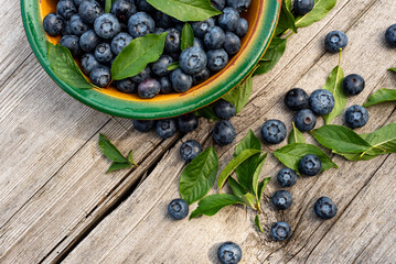 Blueberries lie on a wooden surface in a plate. Blueberries scattered on a wooden table