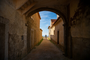Naklejka premium Silhouette of a Man Standing in an Archway Overlooking the Ocean at Santuário de Nossa Senhora do Cabo Espichel, Portugal. December 2024