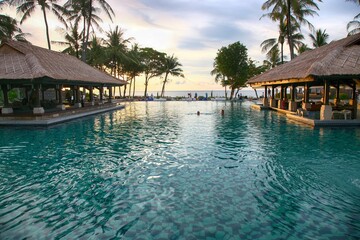 Serenity at Bali seaside resort with inviting pool and palm trees during sunset