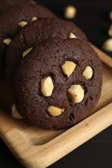 Delicious chocolate cookies with hazelnuts on black table, closeup