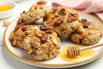 Tasty cookies with nuts and honey dipper on light table, closeup