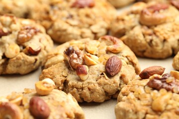 Tasty cookies with nuts on parchment paper, closeup
