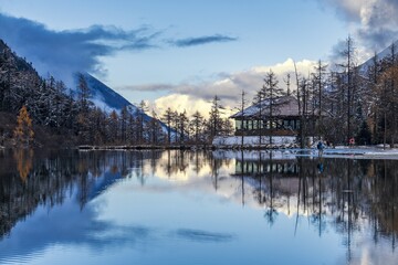 Fototapeta premium Sichuan Aba Prefecture Bipenggou sunset showcases reflections over a tranquil lake and mountains