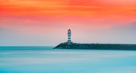 Fototapeta premium Breathtaking evening sunset illuminating lighthouse on serene beach landscape