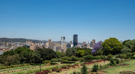 Fototapeta premium Pretoria city view from Union Buildings gardens, high buildings and blooming jacaranda trees. South Africa.