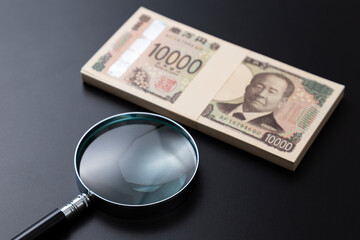 黒背景に虫眼鏡と100万円