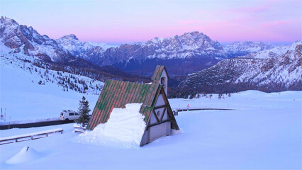 The snow-capped peaks of the Dolomite Alps rising majestically above the church create a harmonious...