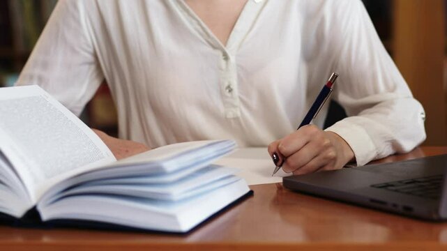A teenage girl writing an essay or taking notes in the library. A perfect scene for studying, exam preparation, and education themes.