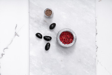 Pink peppercorns, salt, black pepper in bowls on a light background