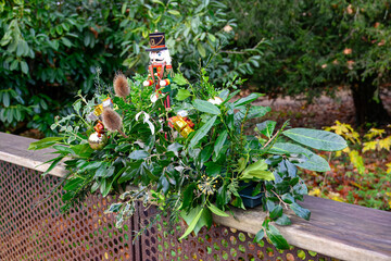 outdoor christmas arrangement made from laurel fir and green leaves with a nutcracker soldier