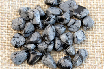 Tumbled close up snowflake obsidian on grey textured background
