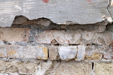 The texture of a very old vintage brick wall with residual elements of plaster decoration