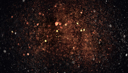 Holiday abstract bokeh on black background. Festive sparkling gold dust. Holiday concept