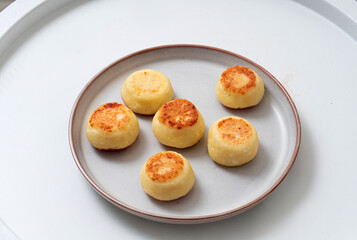 Small syrniki on a plate on a light background