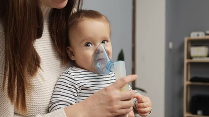 A mother assists her young child with a nasal aspirator to alleviate congestion. The child looks intrigued while exploring this new experience at home in a cozy, modern setting