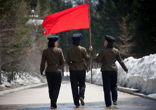North Korean students with a red flag walking on the steps of the nation's heroes in mount Paektu, Ryanggang Province, Samjiyon, North Korea