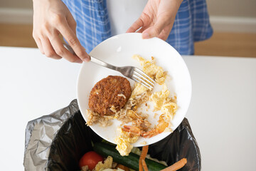 Compost from leftover food, refuse asian young housekeeper woman, girl hand using fork scraping waste from dish, throwing away putting into garbage, trash or bin..Environmentally responsible, ecology.